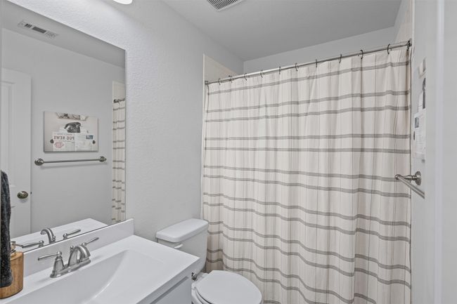 Bathroom with toilet, vanity, a textured wall, and a shower with curtain | Image 28