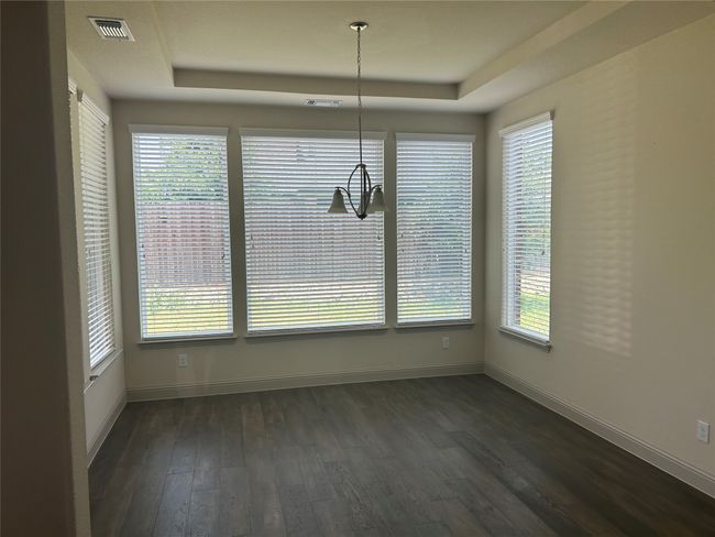 Unfurnished dining area featuring a raised ceiling, dark wood-style floors, baseboards, and a chandelier | Image 7