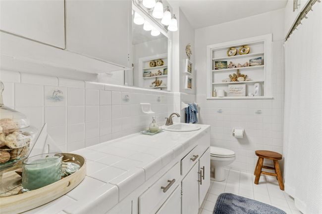 Charming & impeccably maintained full 2nd bathroom featuring ample counter space, great storage options & a fresh, bright atmosphere. | Image 16