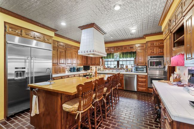 Kitchen featuring an island with sink, stainless steel appliances, crown molding, and wooden counters | Image 12