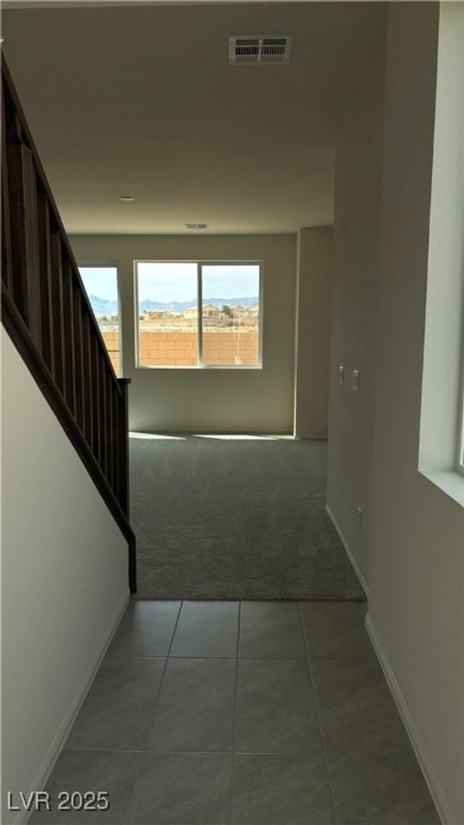 Hallway with carpet floors, stairway, tile patterned floors, baseboards, and visible vents | Image 15