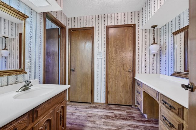 Bathroom with vanity, a textured ceiling, wallpapered walls, and wood finished floors | Image 20