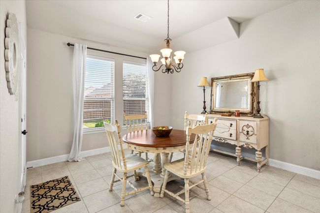 Dining room with light tile patterned floors, a chandelier, visible vents, and baseboards | Image 18