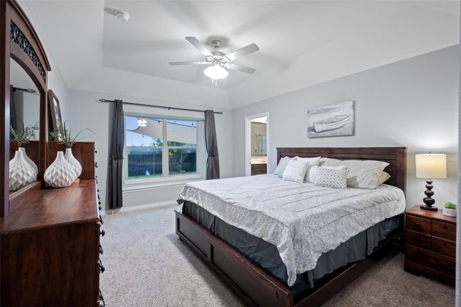 Bedroom with carpet floors, a raised ceiling, a ceiling fan, and baseboards | Image 15