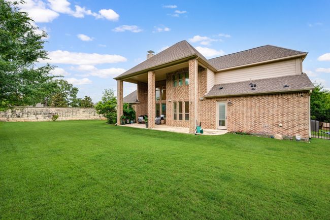 Back of property with a patio area, brick siding, a chimney, and a shingled roof | Image 34