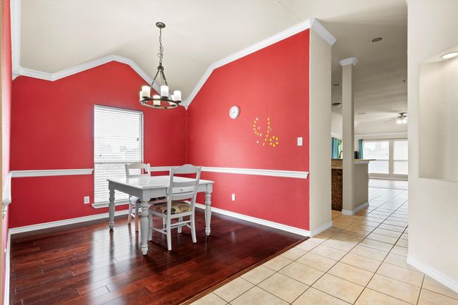 Dining space featuring a chandelier, lofted ceiling, crown molding, wood finished floors, and ceiling fan | Image 10