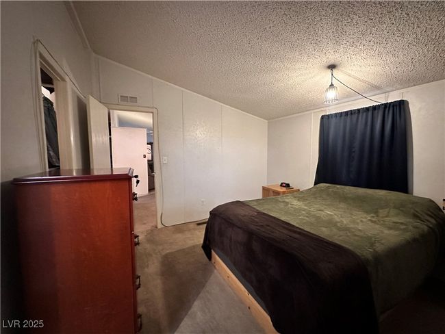 Carpeted bedroom featuring visible vents, a textured ceiling, and vaulted ceiling | Image 11