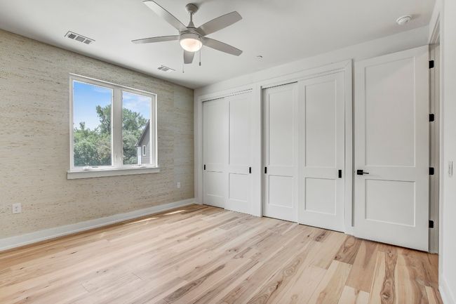 Unfurnished bedroom featuring two closets, light wood-style floors, baseboards, ceiling fan, and wallpapered walls | Image 14
