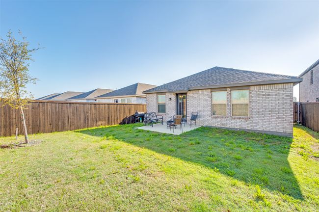 Rear view of property featuring a yard, a fenced backyard, a patio, brick siding, and a shingled roof | Image 22