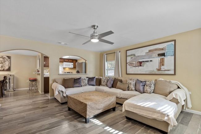 Living room featuring arched walkways, visible vents, a ceiling fan, wood finished floors, and baseboards | Image 14
