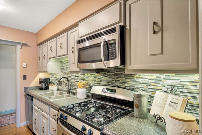 Kitchen featuring tasteful backsplash, a sink, white cabinets, and stainless steel appliances | Image 7