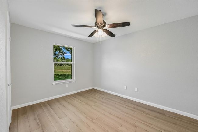 Spare room featuring light wood-type flooring, baseboards, and ceiling fan | Image 13