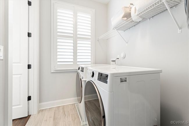 Laundry room with light wood-style flooring, baseboards, washer and clothes dryer, and laundry area | Image 22