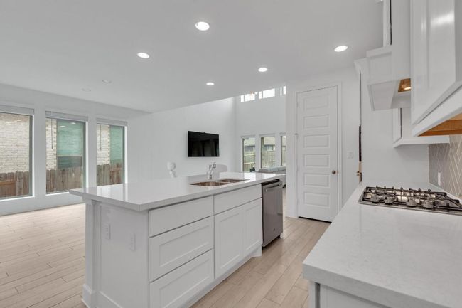 Kitchen with light countertops, white cabinets, recessed lighting, a center island with sink, and light wood-style flooring | Image 11