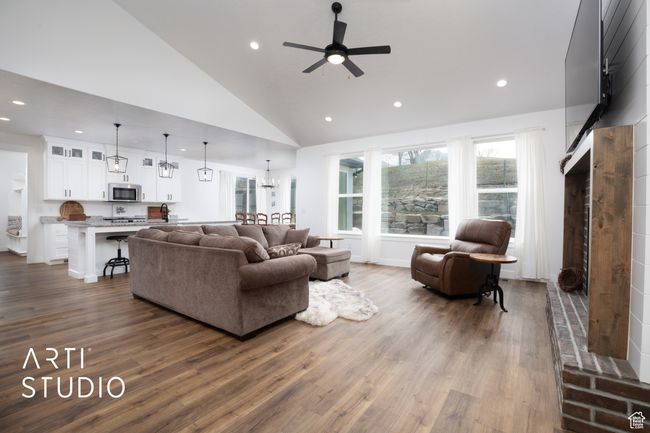 Living room featuring ceiling fan with notable chandelier, wood-type flooring, and high vaulted ceiling | Image 7
