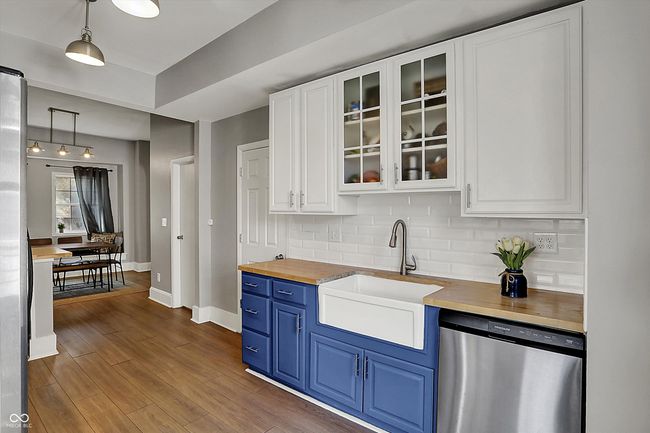 kitchen featuring stainless steel dishwasher, a sink, decorative backsplash, blue cabinetry, and wood counters | Image 19