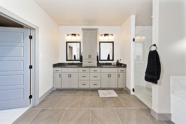 Bathroom featuring a sink, tile patterned floors, a shower stall, and double vanity | Image 23