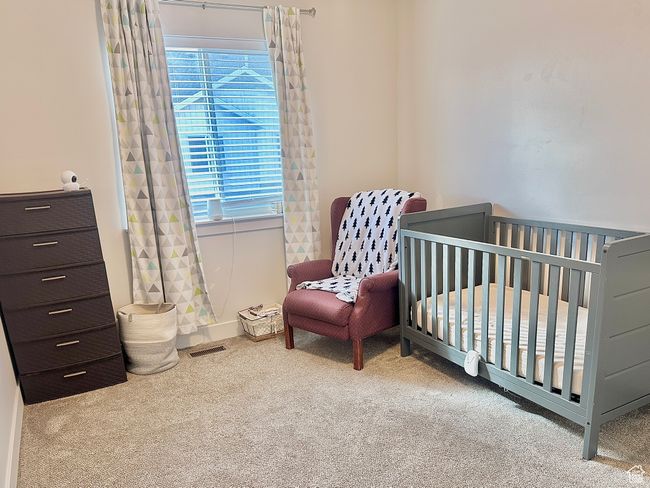 Carpeted bedroom featuring visible vents and a nursery area | Image 8