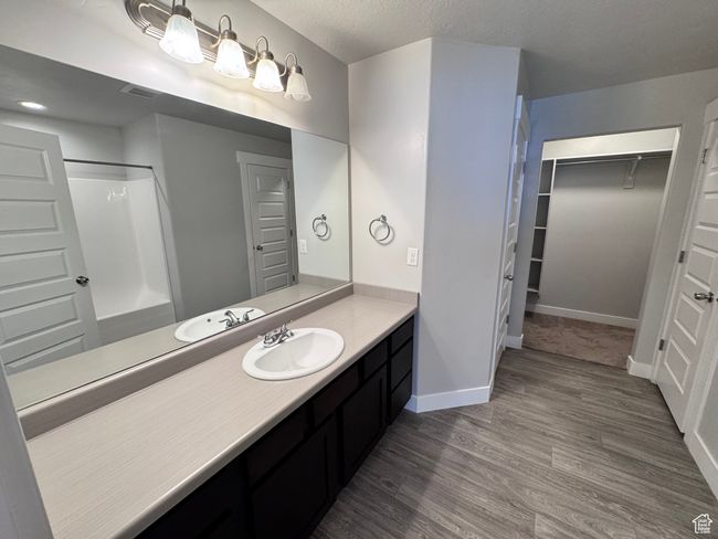 Bathroom featuring vanity, visible vents, baseboards, walk in shower, and wood finished floors | Image 14