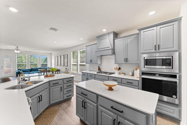 Kitchen featuring appliances with stainless steel finishes, gray cabinets, custom exhaust hood, light countertops, and recessed lighting | Image 10