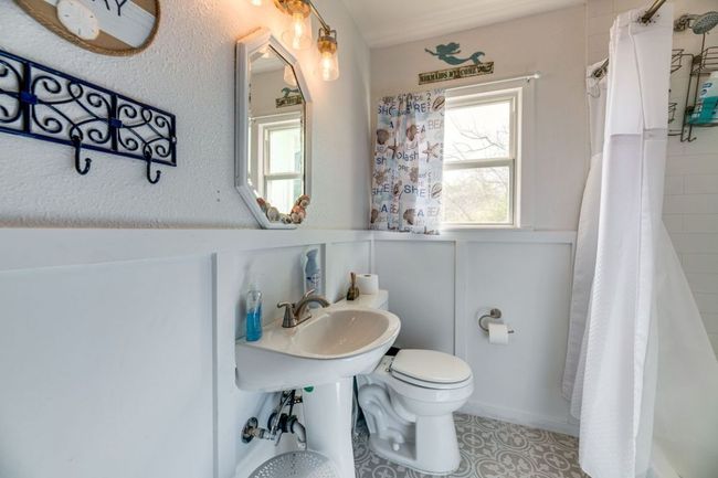 Full bath featuring toilet, a sink, curtained shower, wainscoting, and a decorative wall | Image 20