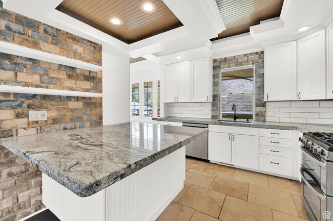 Kitchen with a sink, wood ceiling, a tray ceiling, white cabinets, and appliances with stainless steel finishes | Image 7