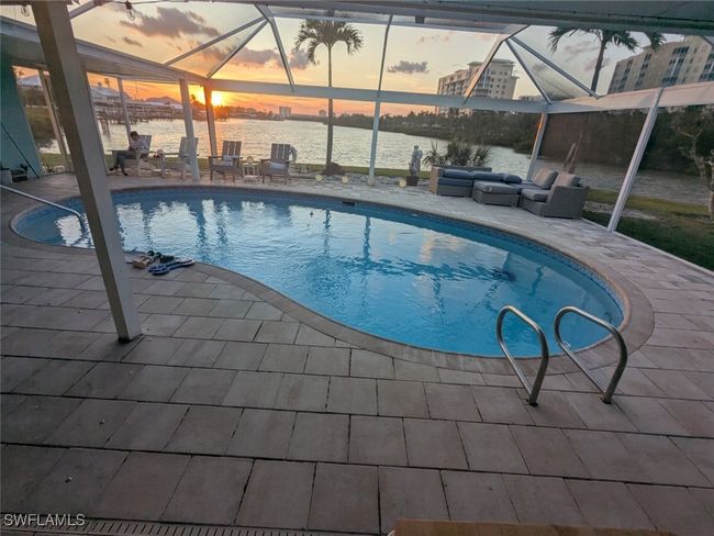 Pool at dusk with a lanai, a water view, and a patio area | Image 14