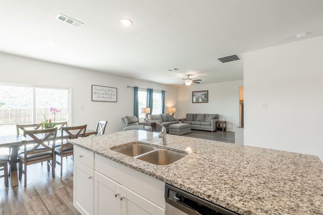 Kitchen with a sink, light stone countertops, white cabinetry, light wood finished floors, and open floor plan | Image 10