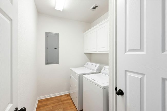 Laundry room featuring electric panel, washing machine and dryer, light wood finished floors, and cabinet space | Image 26
