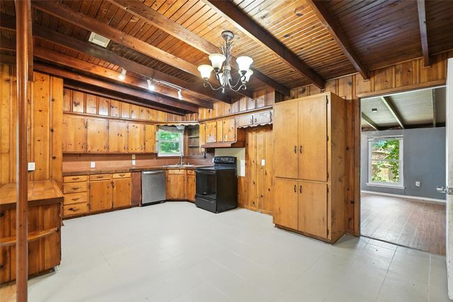 Kitchen featuring black electric range, dishwasher, a wood ceiling with exposed beams, a chandelier, and healthy amount of natural light | Image 16