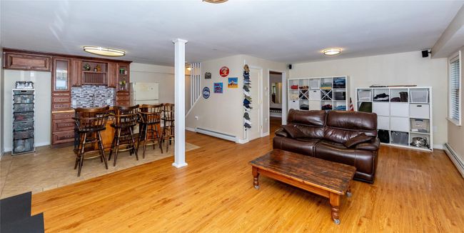 Living area with decorative columns, a baseboard heating unit, light wood-style floors, and a bar | Image 42