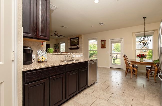 Kitchen featuring a sink, dishwasher, a peninsula, decorative backsplash, and dark brown cabinets | Image 4