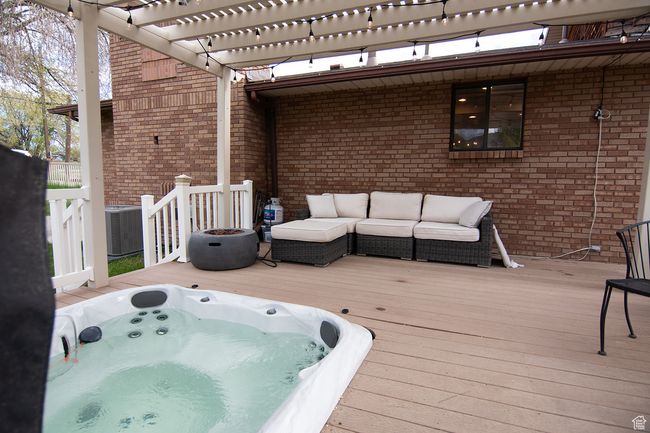 Wooden terrace with outdoor lounge area, a pergola, central AC, and a hot tub | Image 34