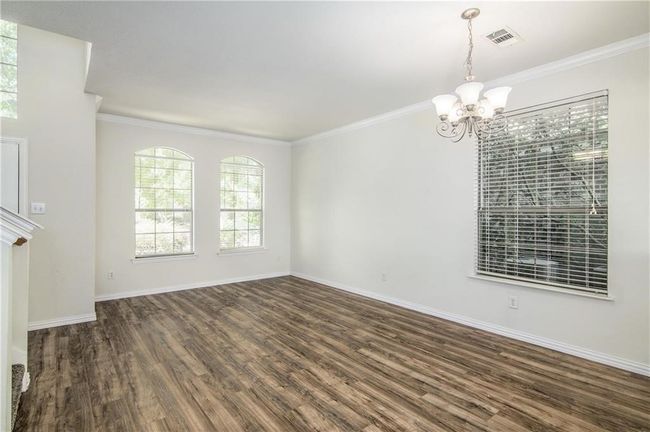 Empty room featuring a chandelier, dark wood-type flooring, and crown molding | Image 6