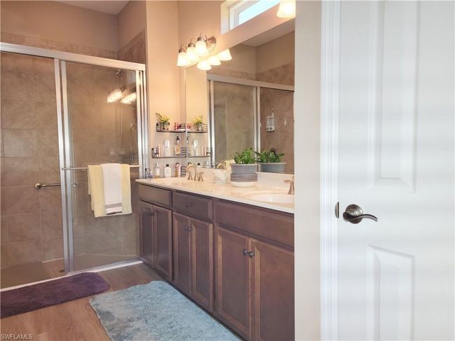 Full bathroom featuring double vanity, a shower stall, wood finished floors, and a sink | Image 29