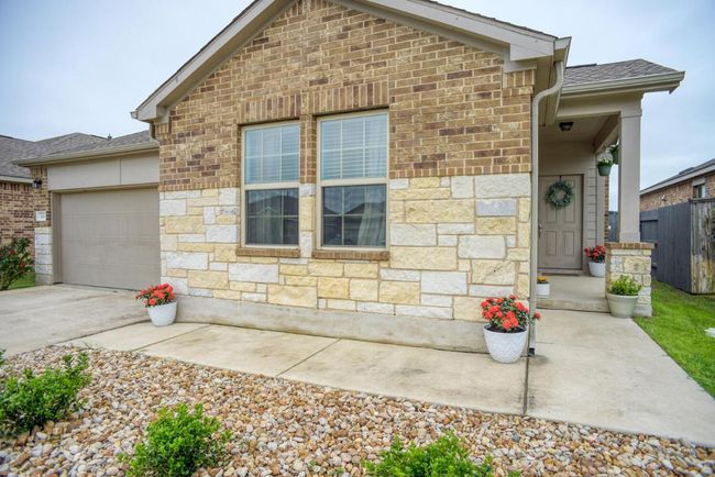 View of front of home featuring driveway, stone siding, an attached garage, fence, and roof with shingles | Image 4