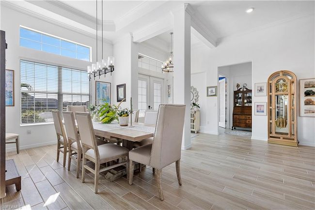 Dining room featuring crown molding, a chandelier, baseboards, a towering ceiling, and wood tiled floor | Image 32