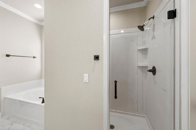 Bathroom with ornamental molding, marble finish floor, a stall shower, and a garden tub | Image 13