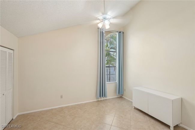 Unfurnished bedroom featuring a closet, light tile patterned flooring, a textured ceiling, vaulted ceiling, and a ceiling fan | Image 24