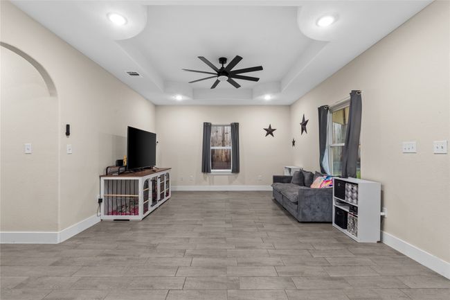 Sitting room with a tray ceiling, arched walkways, ceiling fan, wood finished floors, and recessed lighting | Image 9