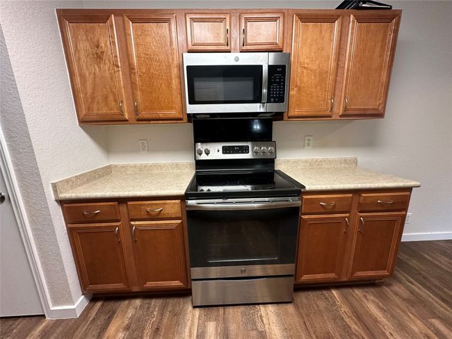 Kitchen with stainless steel appliances, dark wood-type flooring, and light countertops | Image 13