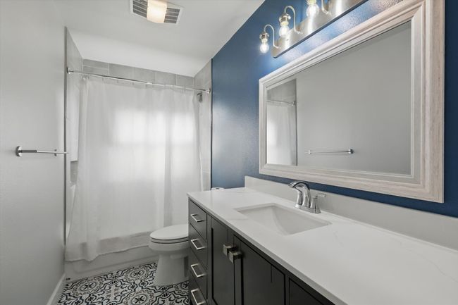 Full bath featuring shower / bath combo, vanity, toilet, tile patterned flooring, and visible vents | Image 29