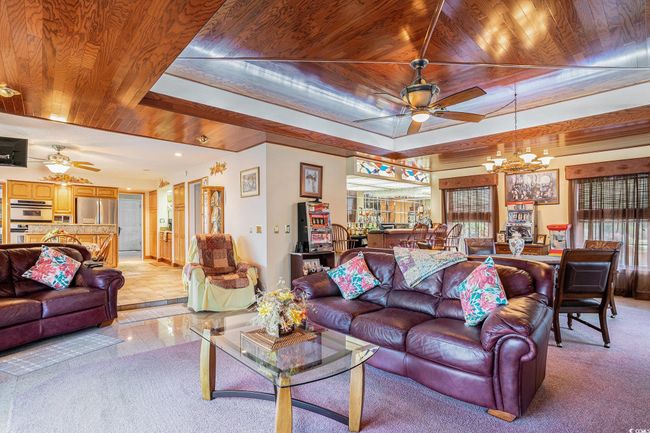 Living area featuring a ceiling fan, wooden ceiling, a chandelier, a tray ceiling, and recessed lighting | Image 14