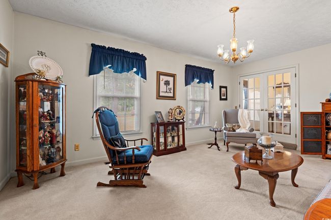 Sitting room with plenty of natural light, french doors, carpet flooring, and a notable chandelier | Image 10