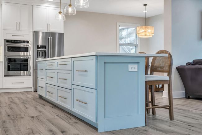 Kitchen with a kitchen bar, a kitchen island, appliances with stainless steel finishes, and light wood finished floors | Image 15