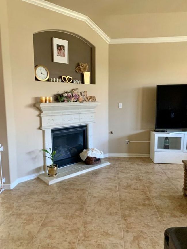 Living room featuring crown molding, a fireplace, baseboards, and tile patterned flooring | Image 5