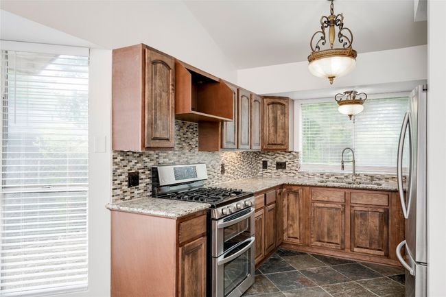 Kitchen with lofted ceiling, backsplash, appliances with stainless steel finishes, and a sink | Image 12