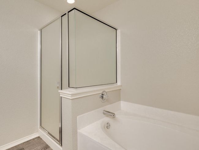 Primary bathroom featuring spacious vanity, luxury vinyl wood-look flooring, separate shower and garden-style tub. | Image 19