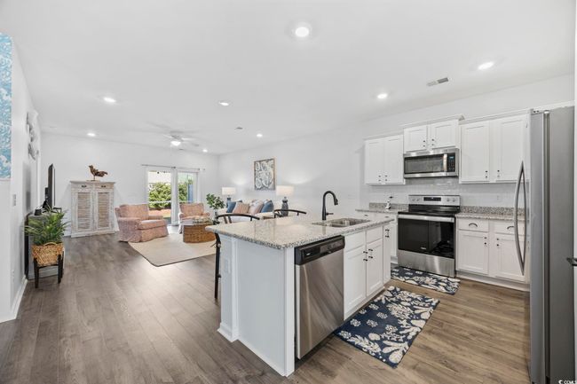 Kitchen with a sink, white cabinetry, open floor plan, stainless steel appliances, and dark wood-type flooring | Image 9
