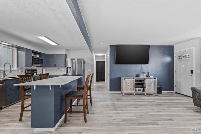 Kitchen with stainless steel appliances, a kitchen breakfast bar, decorative backsplash, light countertops, and light wood finished floors | Image 10